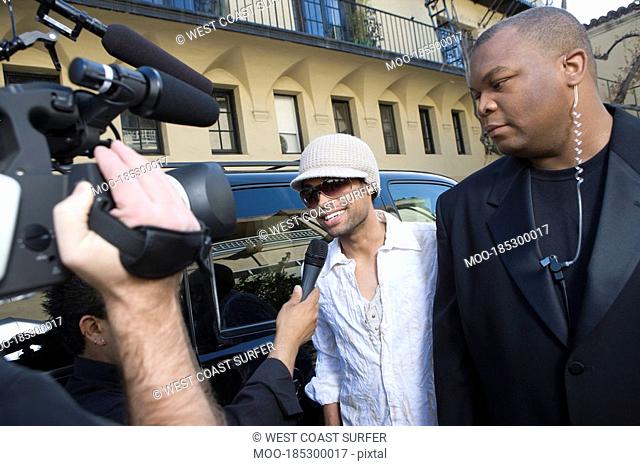 Male celebrity being interviewed by paparazzi
