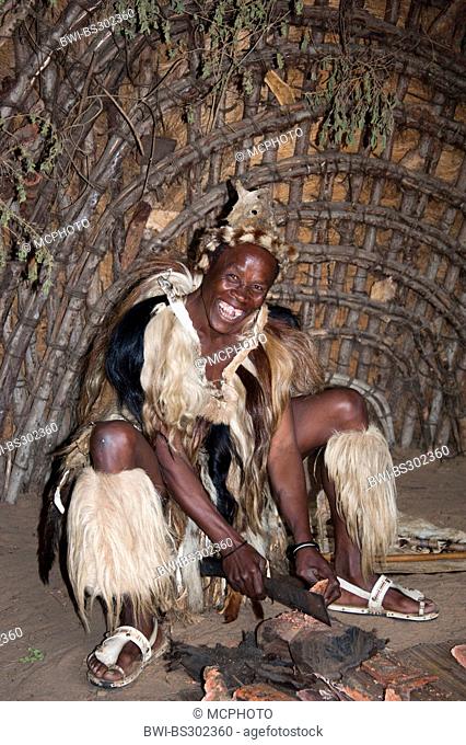 smiling Zulu medicine man making a madizine out of a bark in a traditional house in an open air museum, South Africa, Kwazulu-Natal, DumaZulu