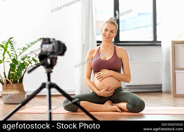 pregnant woman or yoga blogger with camera at home