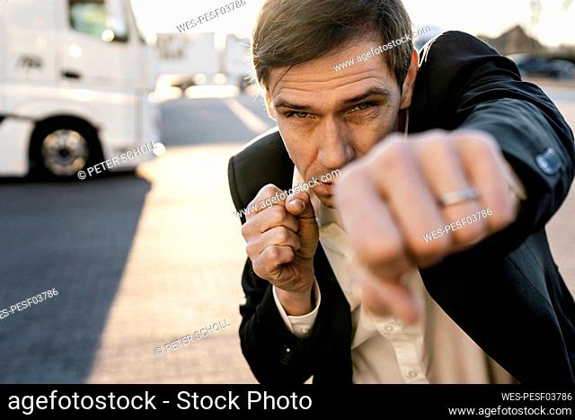 Mature businessman practicing boxing on footpath