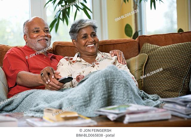 Senior African couple watching television