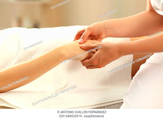 Massage therapist massaging hands of a woman in a spa salon