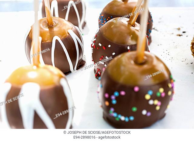 A close up of chocolate coated apples on display in a store