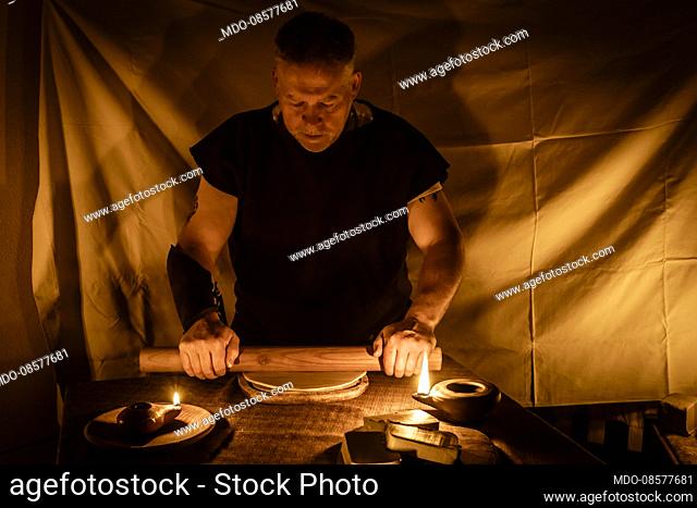 Celts: hypothetical reenactment of the preparation and ongoing of a noble feast. Making the wild boar loin. The cook is rolling out the argile to wrap the meat
