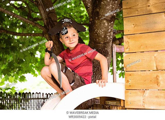 Cute boy in pirate costume sitting on slide