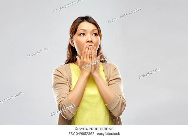 scared asian woman over grey background