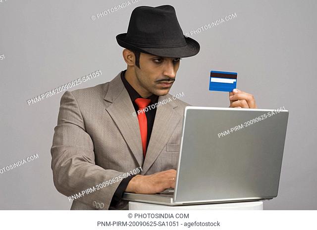 Actor portraying a businessman holding a credit card and working on a laptop