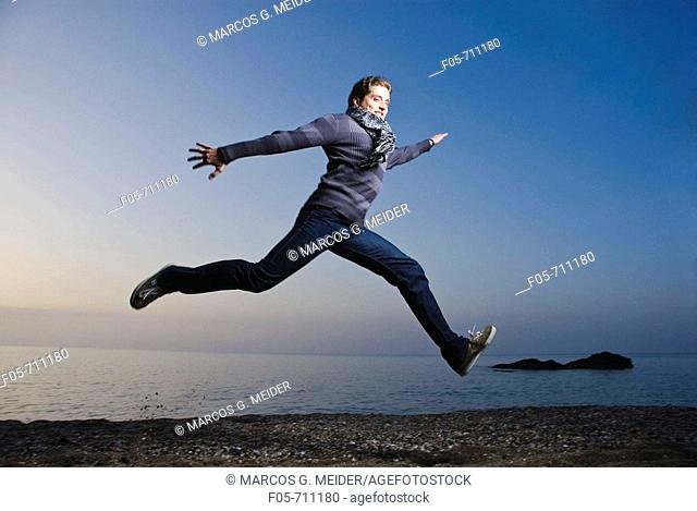 Young man jumping along the seashore at dawn