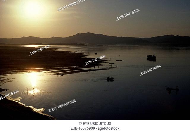 View over Irawaddy river at dusk or dawn with the sun in left corner reflecting off water