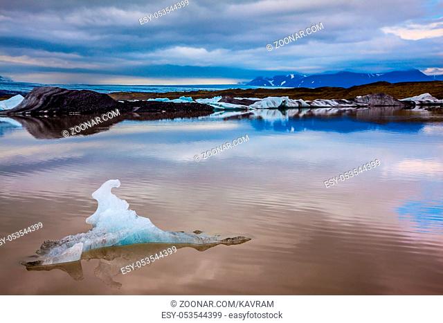 The concept of extreme northern tourism. Glacier meltwater form a picturesque lake, which reflected the cloudy sky. The sunset over the Iceland's largest...