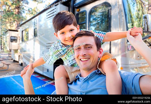 Happy Young Caucasian Father and Son In Front of Their Beautiful RV At The Campground