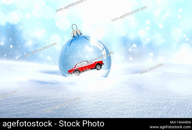 Transparent glass Christmas ball with a red car in the snow