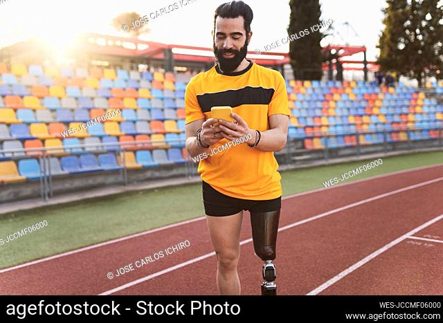 Athlete using mobile phone standing on running track