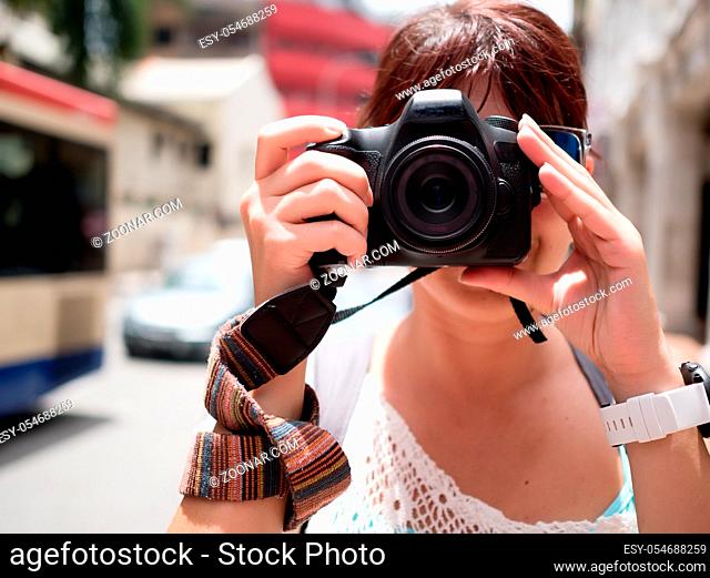 Girl with camera near face on blurred background