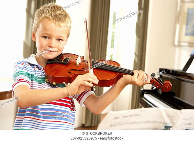 Young boy playing violin at home