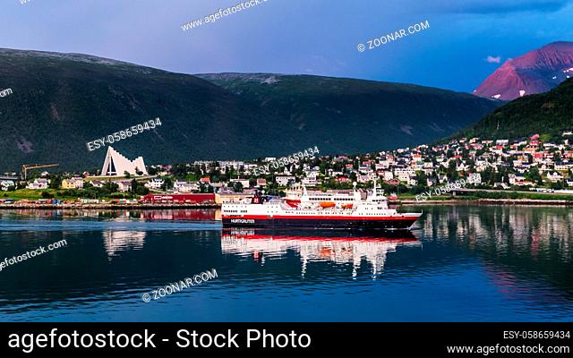 TROMSO, FINLAND - JULY 26, 2016:Skyline with Arctic Cathedral and the Hurtigruten ship navigating into the harbor of Tromso in northern Norway