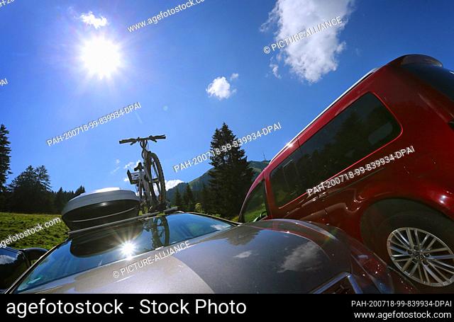 18 July 2020, Bavaria, Rettenberg: Excursionists' cars are parked on the fully occupied parking lot of Alpe Kammeregg in bright sunshine