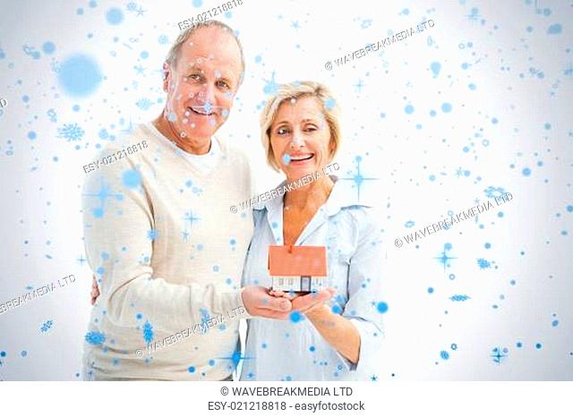 Happy mature couple with model house