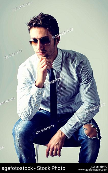A different kind of young business man wearing shirt, tie and ripped jeans, on light background