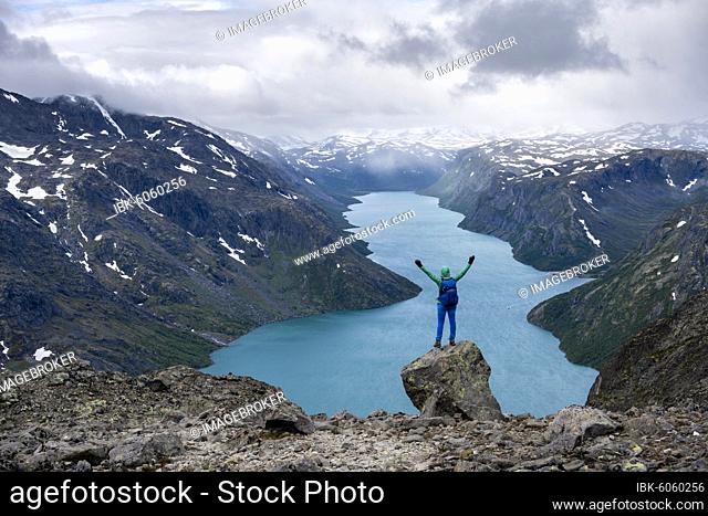 Hiker stands on rocks and stretches arms in the air, Besseggen hike, ridge walk, Lake Gjende, Jotunheimen National Park, Vågå, Innlandet, Norway, Europe