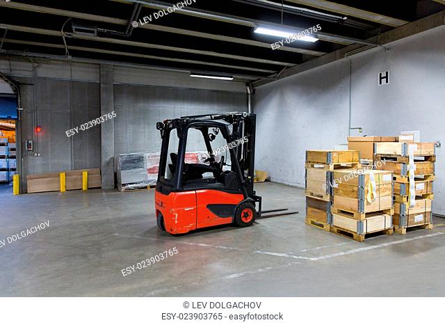 logistic, storage, loading, shipment and equipment concept - forklift loader and boxes at warehouse