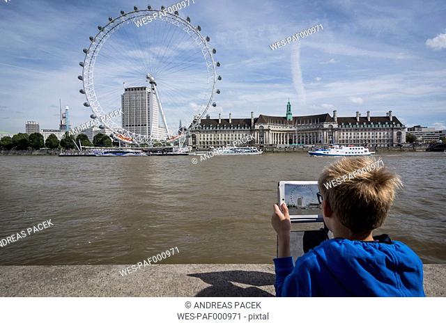 UK, London, boy photographing the London Eye with his digital tablet