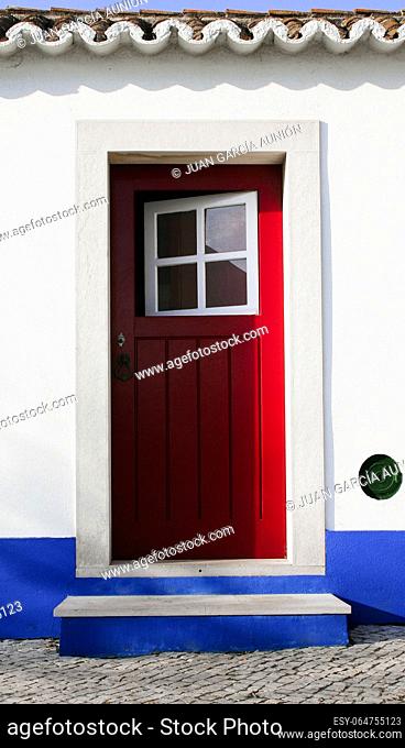 Tiny door painted with vivid colors at Vila Nova de Milfontes house. Little picturesque town on the Alentejo coast, Portugal