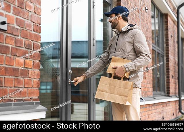 happy food delivery man with paper bags at door