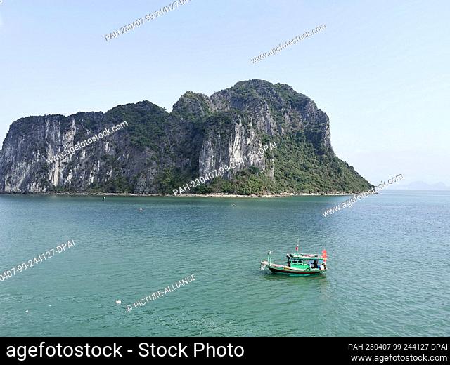 01 March 2023, Vietnam, Halong-Bucht: A small fishing boat sails in Halong Bay. Halong Bay (Vietnamese: Vinh Ha Long) is an area of about 1