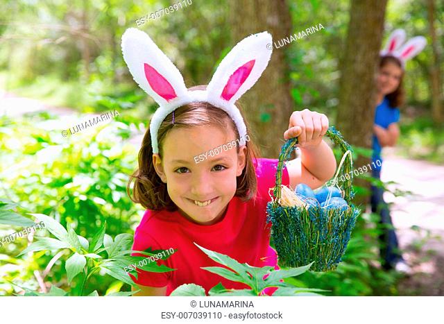 Easter girl with eggs basket and funny bunny face expression at the forest
