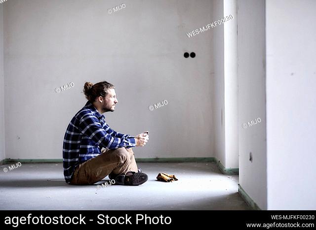 Worker on a construction site sitting on the floor holding tablet