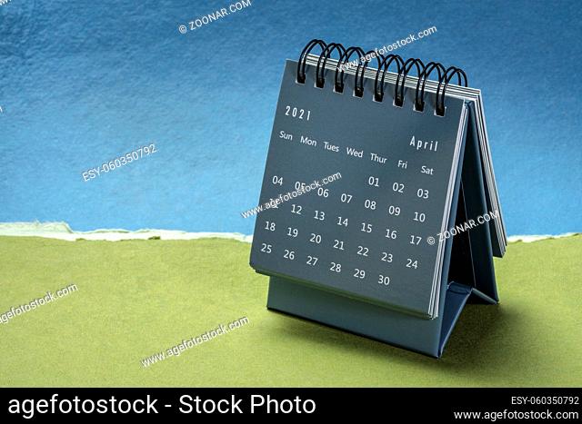 April 2021 - spiral desktop calendar against paper landscape abstract, time and business concept