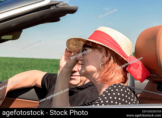 Beautiful older woman with a sun hat and her partner in a car