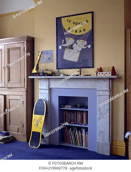 Scateboard leaning against marble fireplace with books on integral blue shelves in child's bedroom with Babar poster