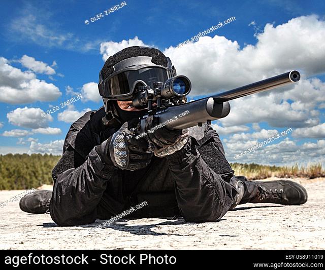 Swat police operator with sniper rifle in black uniforms pointing criminals terrorists waiting in stakeout. Low angle view