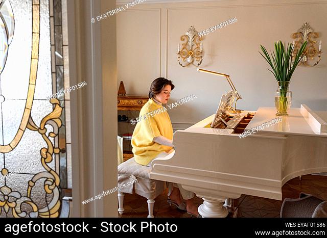 Young woman playing grand piano at home