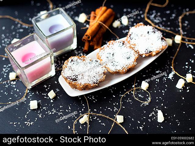 coconut cupcakes and candles on a black background with cinnamon sticks and bits of candied fruit