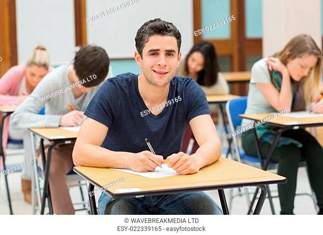 Man looking up from sitting exam and smiling in college
