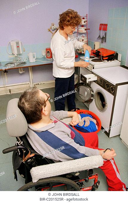 Carer doing washing in kitchen with man with Cerebral Palsy, who is wheelchair user
