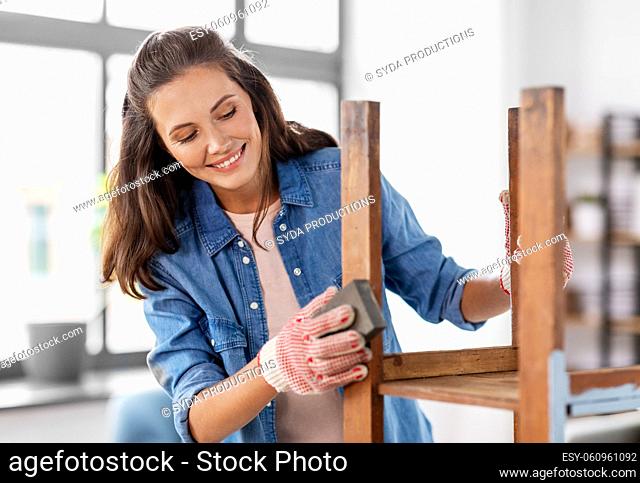 woman sanding old round wooden table with sponge