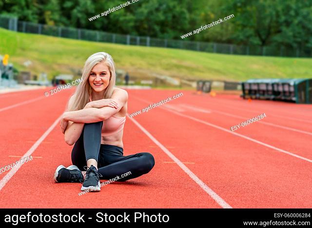 A beautiful young college athlete prepares herself for a track meet at a local university