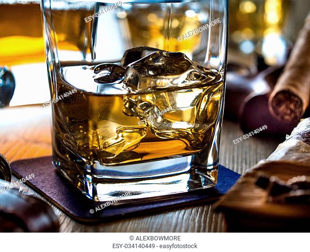 One glass of whiskey on the rocks on a wooden table