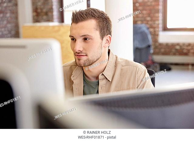 Young man sitting in office using computer