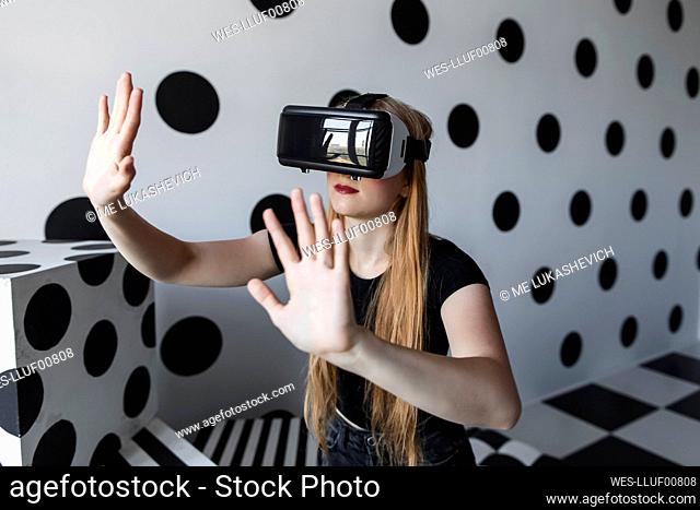 Girl gesturing wearing virtual reality headset by wall
