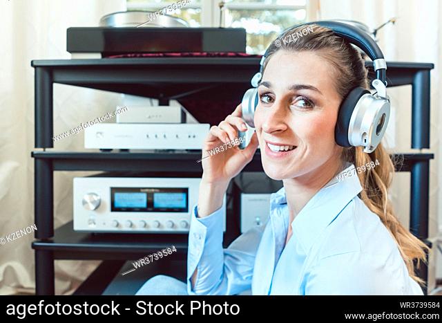 Audiophile woman enjoying music in her home looking at the camera