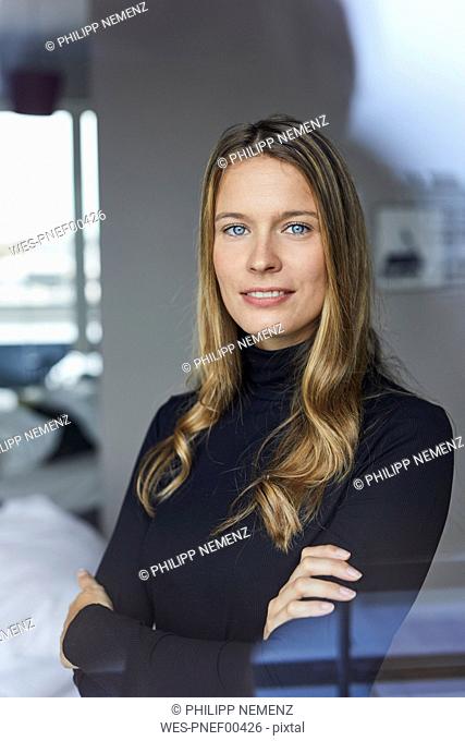 Portrait of smiling young woman wearing black turtleneck behind windowpane