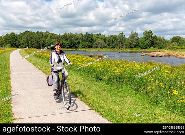 Woman at bike in Dutch national park with forest and wetlands