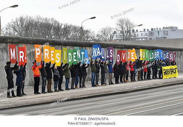 'Mr. President, Walls divide. Build bridges!' can be read on posters held up by Greenpeace activists on Bernauer-Strasse in Berlin,  Germany, 20 January 2017