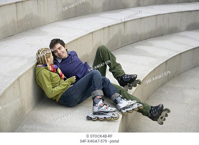 Young couple wearing Inline skates sitting on a staircase