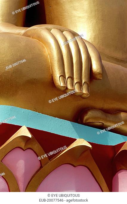 Large golden seated Buddha with detail of hand and colourful base